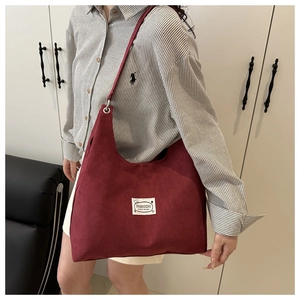 Detailed close-up of burgundy suede tote bag showing fabric texture and fashion label