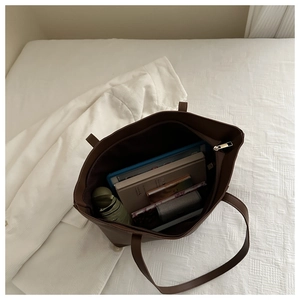 Detailed interior of a large brown tote bag showing capacity for tablets and essentials