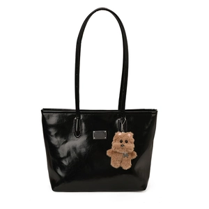 Bolso tote de cuero negro brillante con placa de metal y colgante de oso de peluche