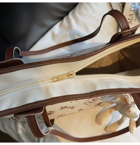 Detail view of canvas tote bag with brown leather trim and cute rabbit charm