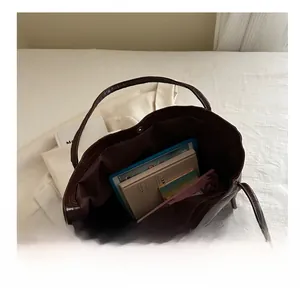 Detail view of the spacious interior of a dark brown crocodile texture tote bag with essentials
