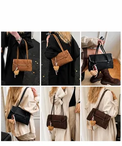 Detail view of large rectangular suede shoulder bag featuring slender straps and bear charm
