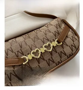 Dettaglio del tessuto jacquard monogramma marrone e catena a cuore dorata della borsa