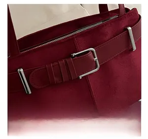 Detailed macro shot of vintage red suede handbag with silver metal buckle and zip closure