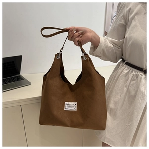 Dettaglio borsa tote in velluto marrone con etichetta moda e design orso per il lavoro