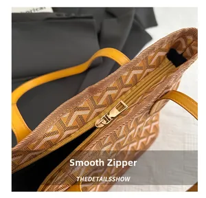 Detailed close-up of smooth gold zipper closure on yellow patterned leather shoulder bag