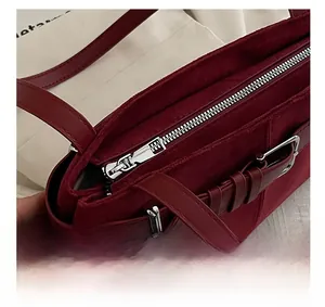 Detail of silver metal zipper closure on a dark red suede textured tote bag