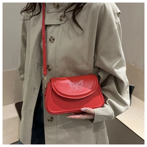 Détail du sac bandoulière rouge avec broderie papillon blanc sur cuir lisse brillant
