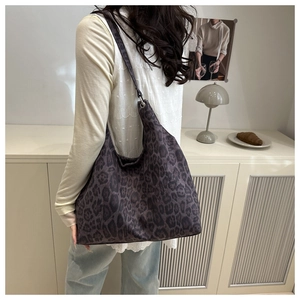 Detail of a large leopard print shoulder bag featuring metallic eyelet accents and thick fabric