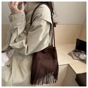 Détail du sac seau en daim marron foncé avec de longues franges et bandoulière