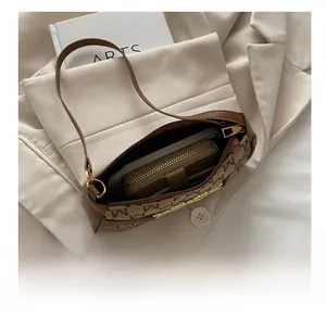 Vista interna della borsa hobo marrone con monogramma che mostra spazio per telefono e portafoglio