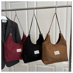 Detailed view of burgundy, black, and brown matte tote bags with minimalist fashion labels