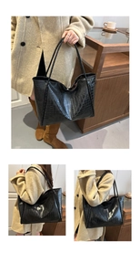 Detail of a black crocodile pattern tote bag with polished texture and long shoulder straps