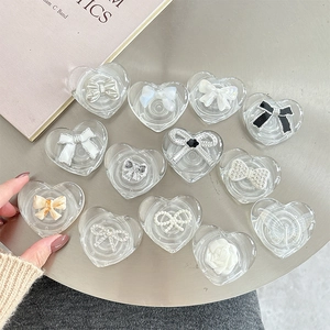 Transparent heart-shaped phone grips with various bow designs shown on a metal table