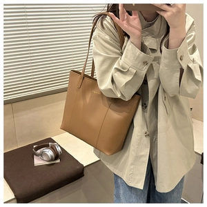 Detail of caramel leather tote bag showing smooth texture and golden logo embossing