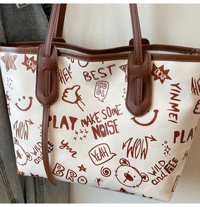 Detail of cute doodle tote bag with brown handles and stylish cartoon character prints