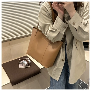 Close-up of caramel leather tote bag with gold brand lettering and soft grain texture