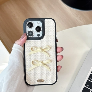 Close-up of beige woven leather iPhone case with double bows and metal text detail