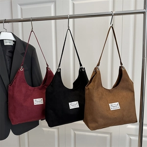 Minimalist faux suede tote bags in burgundy, black, and tan colors on a display stand
