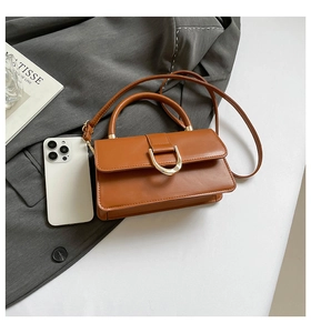 Detailansicht braune Lederhandtasche mit goldener D-Ring Schnalle und Schultergurt