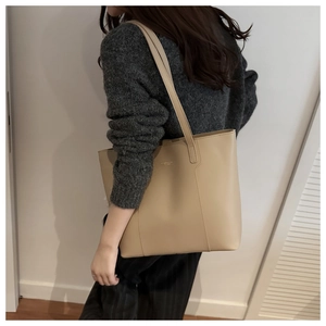 Detail shot of the matte beige leather texture and logo on this large commute tote bag