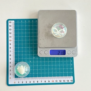 Detailed view of resin phone grip charms showing weight and size on measurement tools