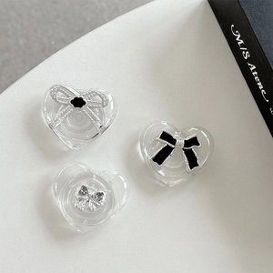 Transparent heart-shaped cell phone grip with silver and black bow decorative elements