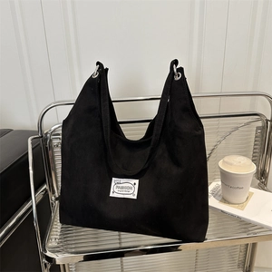 Minimalist black canvas tote bag with fashion label on a modern metal shelf