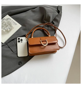 Detail der braunen Ledertasche mit goldener D-Schnalle und verstellbarem Riemen