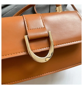 Detail der braunen Lederhandtasche mit einer goldenen hufeisenförmigen Magnetschnalle