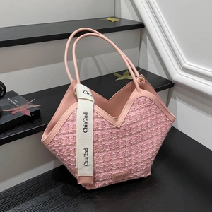Pink tweed tote bag with leather handles and white ribbon detail on dark wooden steps