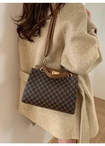 On-body shot of a brown plaid crossbody bag with a metal buckle and leather strap