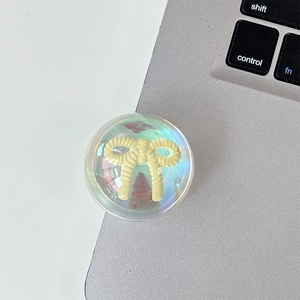 Iridescent bear phone grip detail with yellow bow on laptop keyboard background