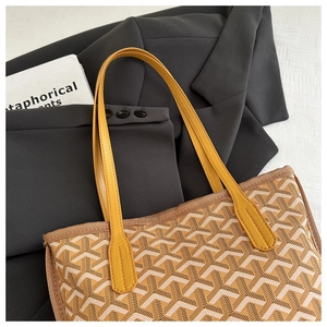 Close-up of the yellow leather handle and iconic Y-pattern printed tote bag detail
