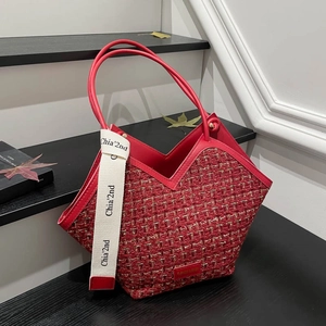 Large red tweed tote bag with leather handles and decorative white logo ribbon strap