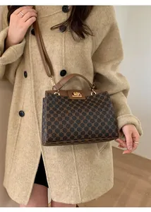 Close-up of golden metallic twist lock on vintage plaid pattern crossbody bag
