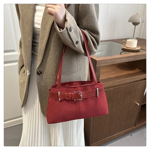 Detail of dark red suede tote bag with retro belt buckle and long leather straps