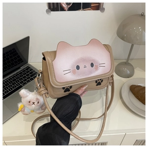Detail of cute cat shaped crossbody bag with paw prints and plush bear accessory