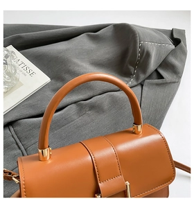 Detailaufnahme der braunen Lederhandtasche mit goldenen Beschlägen und Tragegriff