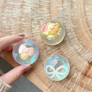 Kawaii clear resin phone grips with bear and bow designs on a wooden surface