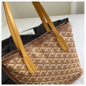 Detail of yellow and brown woven Y-pattern tote bag with premium leather handles