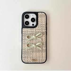 Close-up of beige tweed iPhone case featuring fabric bows and golden metal plate detail