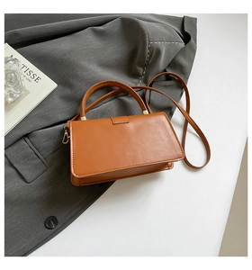 Details der karamellbraunen quadratischen Handtasche mit Lederstruktur und Goldbeschlägen