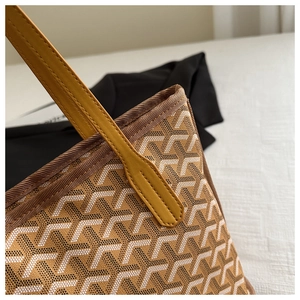 Detailed close-up of yellow leather handles and Y-patterned canvas on a large tote bag