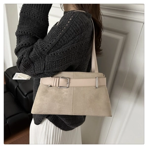 Detail of beige suede shoulder bag with leather belt buckle in a minimalist interior