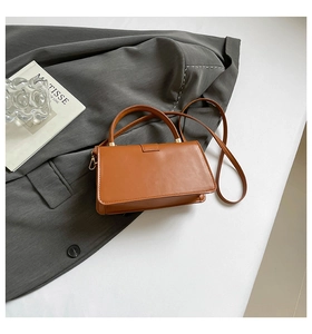 Draufsicht auf eine braune Lederhandtasche auf einem Blazer mit Griff und Riemendetails