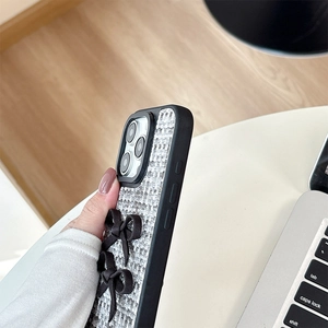 Detail of woven fabric iPhone case with dual black silk bows and raised camera protection