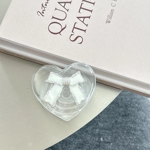 Detailed view of heart-shaped transparent phone grip with white bow and silver edges