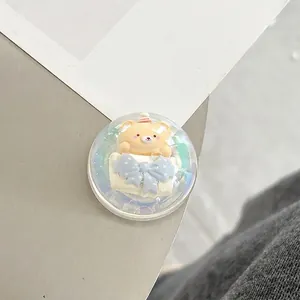 Close-up of a 3D cartoon bear acrylic phone grip with a cute pink party hat and blue bow