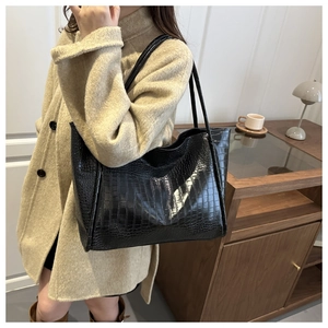 Close-up of black crocodile embossed tote bag with wide opening and slim shoulder straps